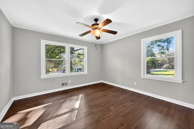 a view of an empty room with window and wooden floor