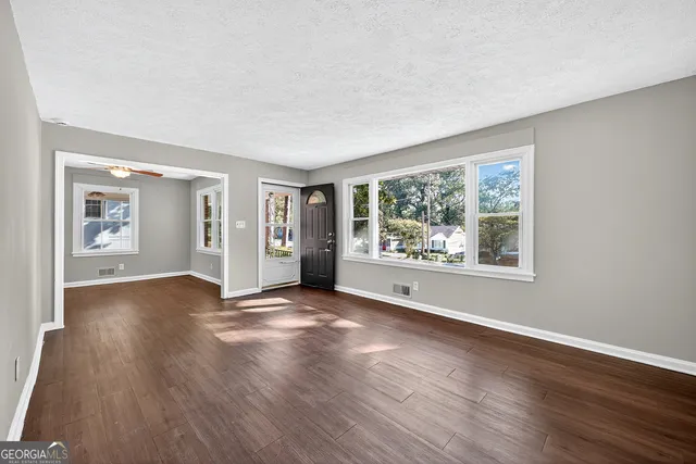 a view of an empty room with wooden floor and a window