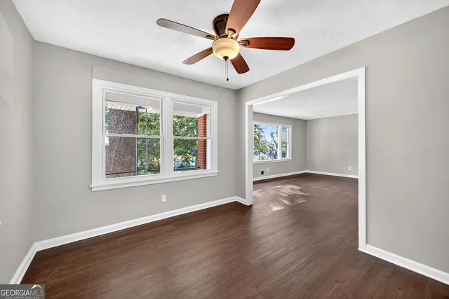 a view of an empty room with wooden floor and a window