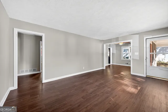 a view of an empty room with wooden floor and a window