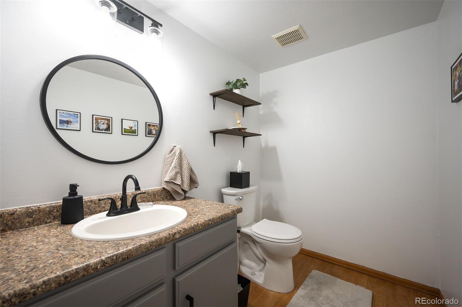 4367 East Maplewood Way Centennial, CO 80121 - Photo 13 of 26 a bathroom with a granite countertop toilet a sink and a mirror