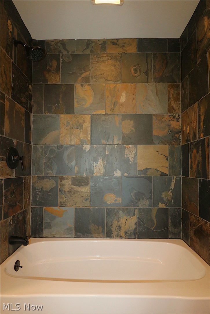 5236 Zenobia Road Wakeman, OH 44889 - Photo 12 of 31 Bathtub with slate-style tiled surround featuring a bronze shower head and faucet fixtures