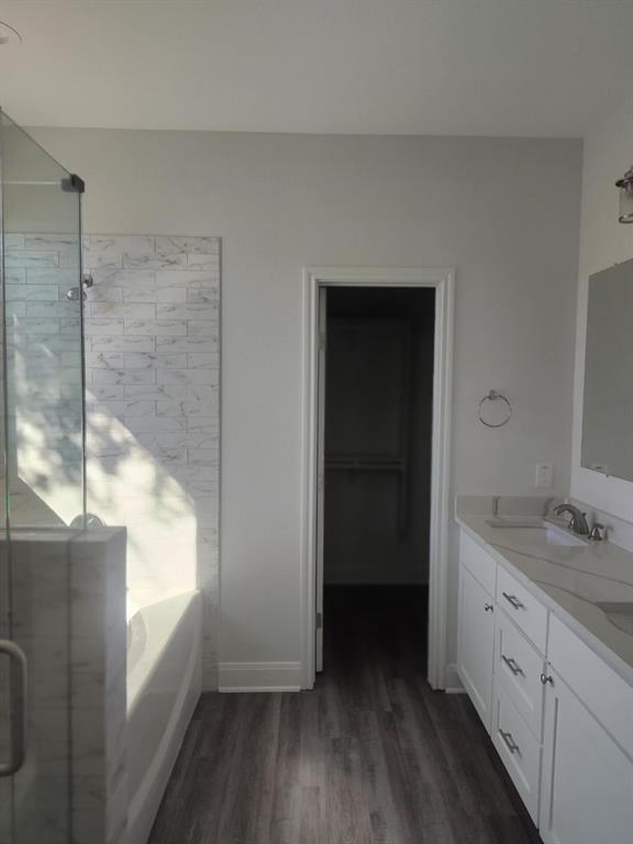 20008 Boggy Ford Road Lago Vista, TX 78645 - Photo 8 of 17 Full bathroom featuring a bath, double vanity, a shower stall, a spacious closet, and dark wood-type flooring