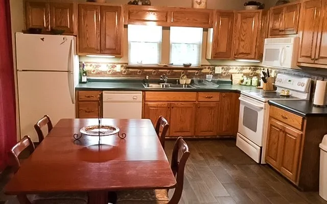 a kitchen with stainless steel appliances granite countertop a sink a stove a refrigerator a microwave oven with white cabinets and wooden floor