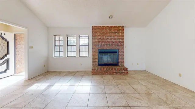 an empty room with windows and fireplace