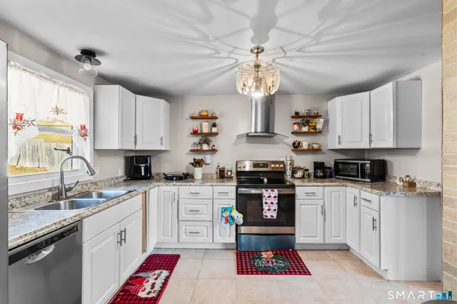 a kitchen with stainless steel appliances granite countertop a sink a stove a refrigerator cabinets and a window