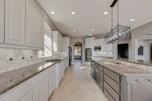 a large kitchen with stainless steel appliances granite countertop a sink and dishwasher a stove with wooden floor