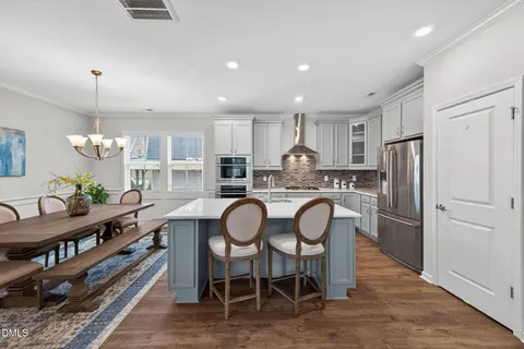 a kitchen with stainless steel appliances granite countertop a dining table chairs refrigerator and cabinets