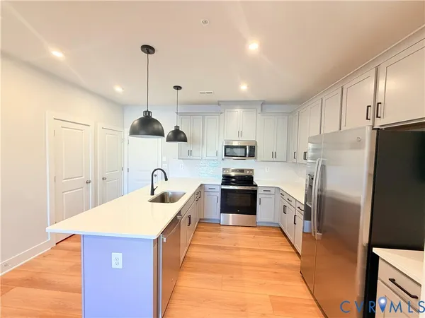 a kitchen with stainless steel appliances granite countertop a refrigerator a stove top oven a sink and dishwasher