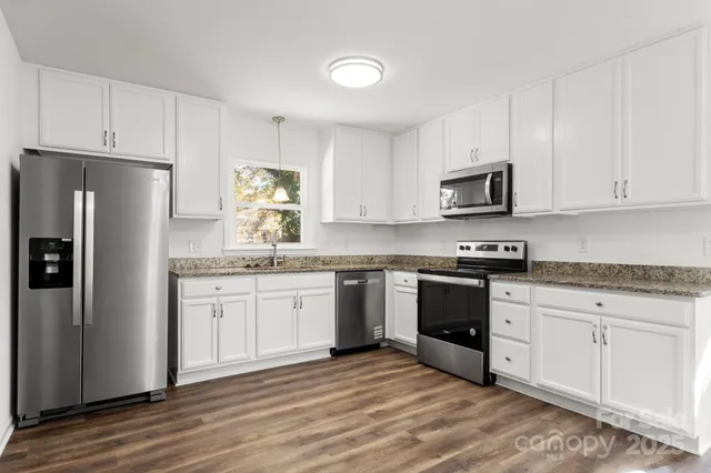 a kitchen with granite countertop white cabinets and stainless steel appliances