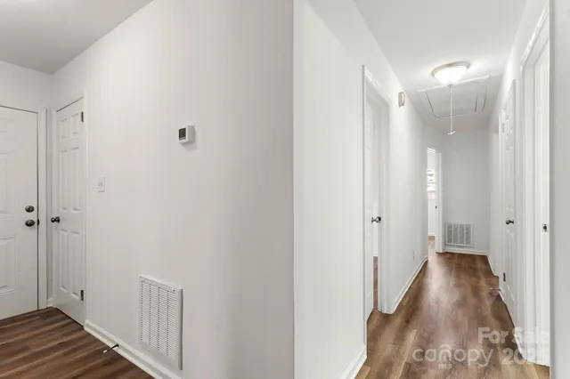 a view of a hallway with wooden floor and a bathroom