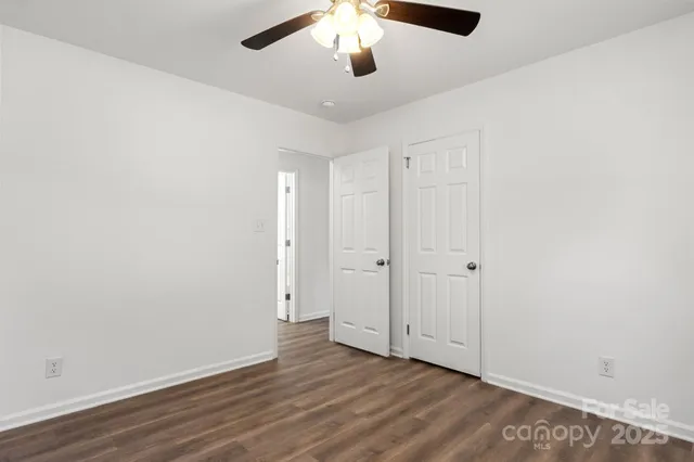 an empty room with wooden floor chandelier fan and closet area