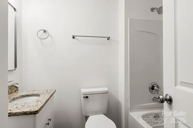 a bathroom with a granite countertop sink and a toilet