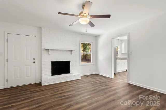 an empty room with wooden floor a ceiling fan and windows