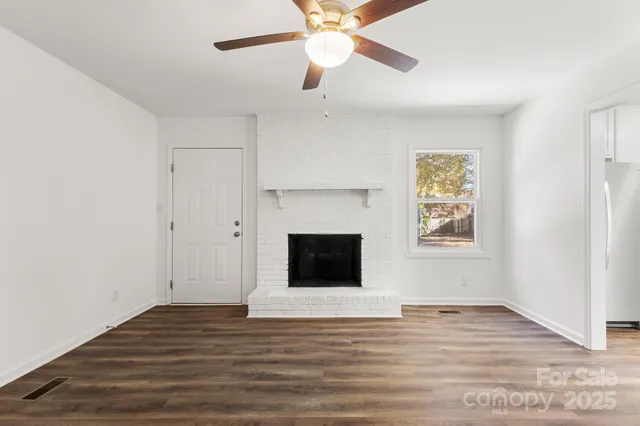 an empty room with wooden floor a ceiling fan and windows