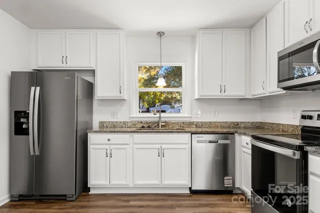 a kitchen with stainless steel appliances granite countertop a refrigerator and a stove top oven