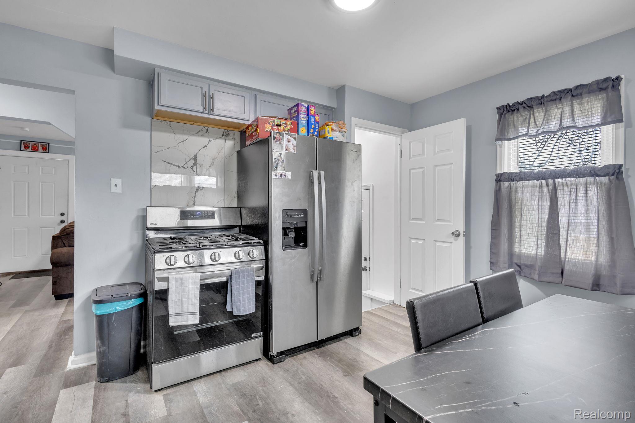 8401 Fielding Street Detroit, MI 48228 - Photo 8 of 34 Kitchen featuring stainless steel appliances, light wood-type flooring, gray cabinets, and tasteful backsplash
