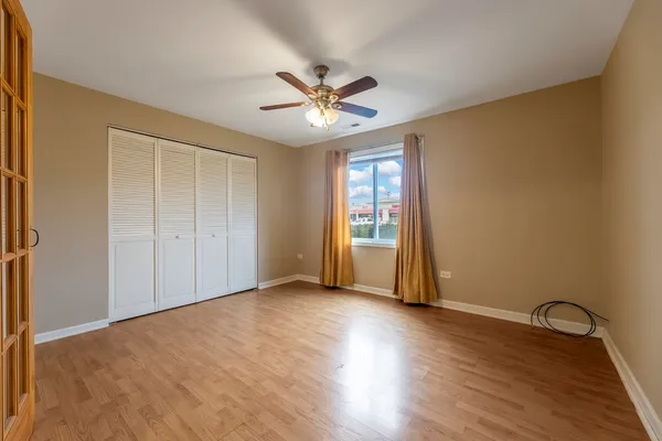 an empty room with wooden floor closet and windows