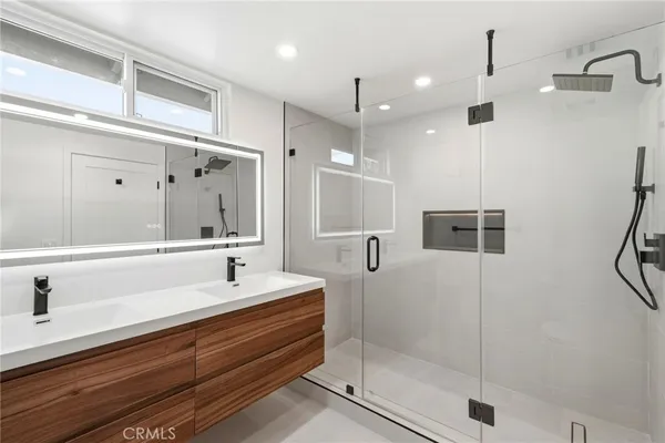a bathroom with a double vanity sink a mirror and shower