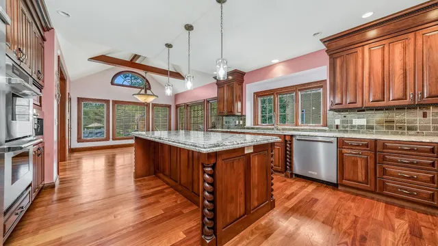 a kitchen with stainless steel appliances granite countertop a sink a stove and a wooden cabinets