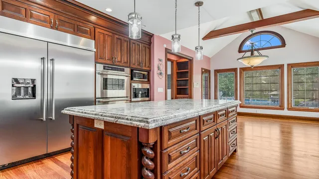 a kitchen with stainless steel appliances granite countertop a stove refrigerator and a wooden cabinets