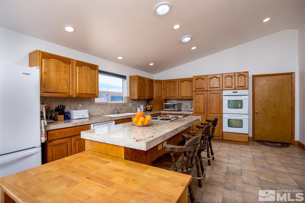 1719 Sunrise Pass Road Minden, NV 89423 - Photo 7 of 39 a kitchen with stainless steel appliances granite countertop a table chairs sink and cabinets
