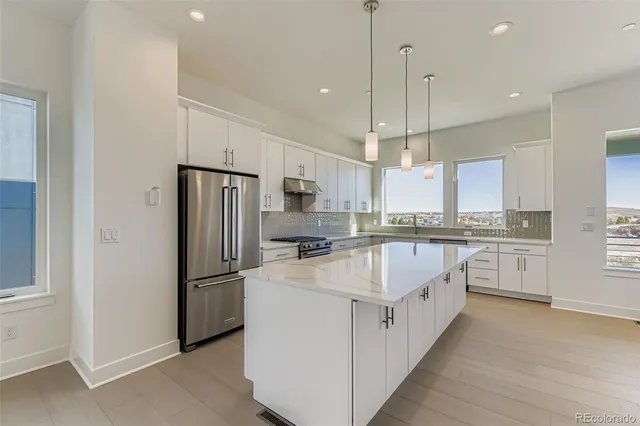 a large kitchen with stainless steel appliances granite countertop a refrigerator a oven and white cabinets