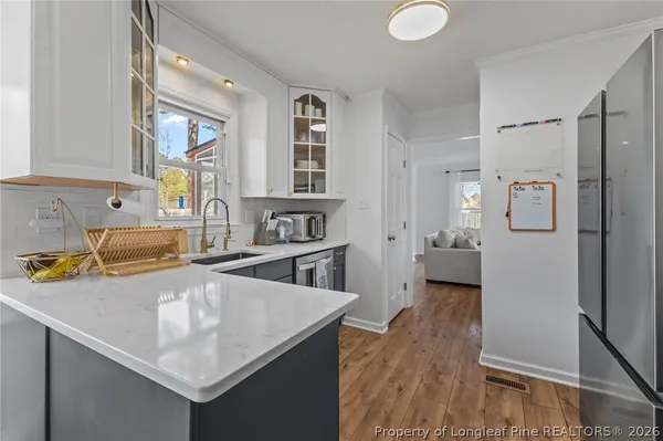 a kitchen with stainless steel appliances granite countertop a sink dishwasher and a refrigerator with wooden floor