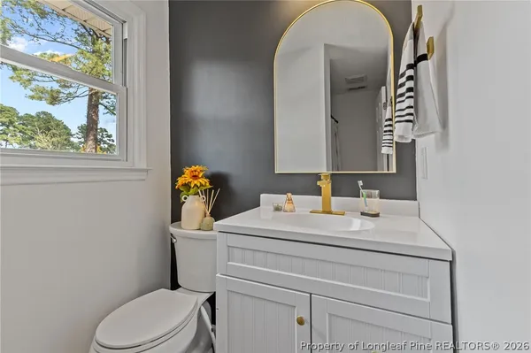 a bathroom with a toilet sink vanity and mirror