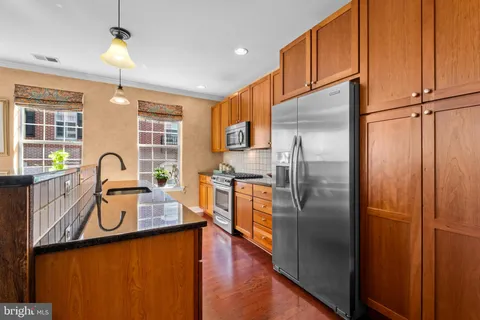a kitchen with stainless steel appliances granite countertop a refrigerator a stove and a sink with wooden floor
