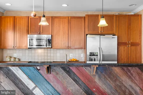 a kitchen with stainless steel appliances granite countertop a refrigerator a sink dishwasher a dining table and chairs with wooden floor