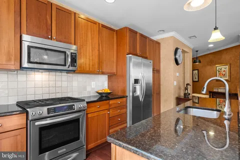 a kitchen with stainless steel appliances granite countertop a sink a stove and a microwave