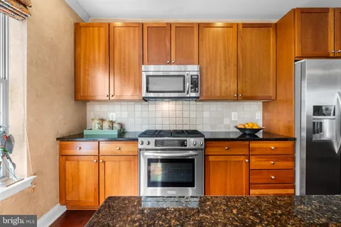 a kitchen with granite countertop wooden cabinets and a stove top oven