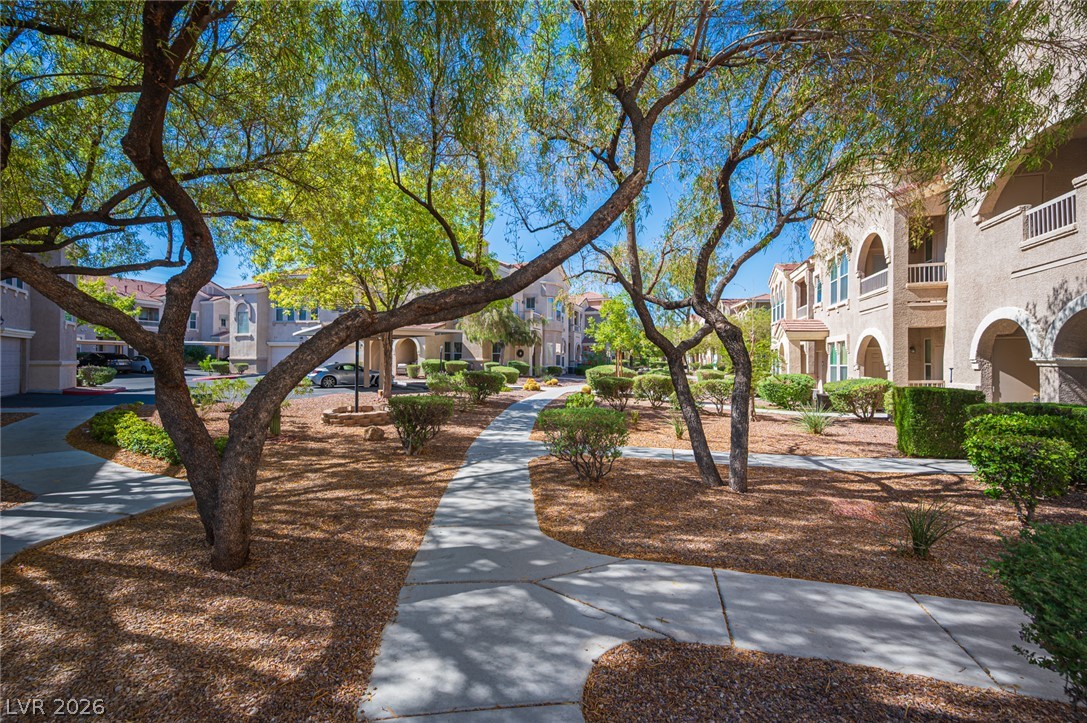 Winding concrete pathways meander through beautifully landscaped common areas shaded by mature trees.