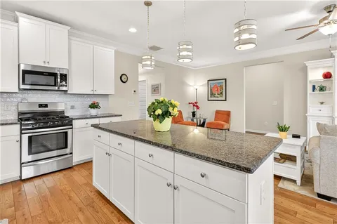 a kitchen with stainless steel appliances granite countertop a kitchen island a stove and a wooden floors
