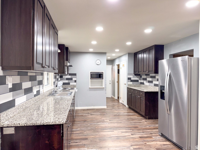 43 A Street Helper, UT 84526 - Photo 3 of 21 Kitchen featuring dark wood-finish cabinetry, light-toned countertops, a mosaic tile backsplash, wood-finish flooring, and recessed lighting