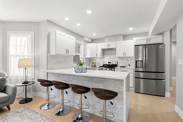 a kitchen with stainless steel appliances granite countertop a refrigerator a stove a sink dishwasher and white cabinets with wooden floor