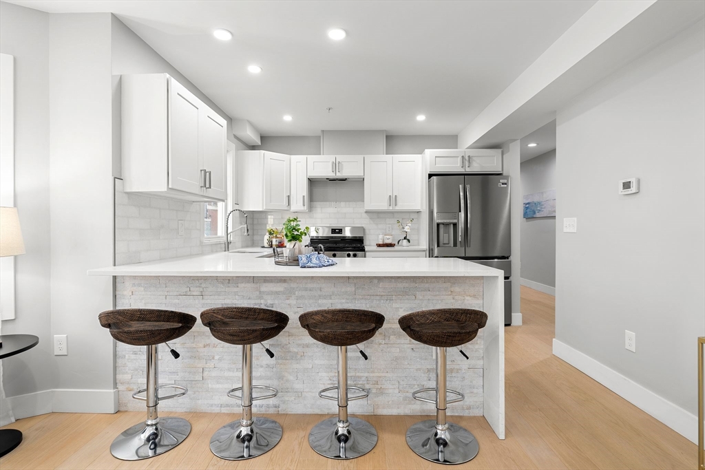 679-683 Columbia Road, Unit 1 Boston, MA 02125 - Photo 7 of 31 a kitchen with stainless steel appliances granite countertop a dining table chairs and white cabinets