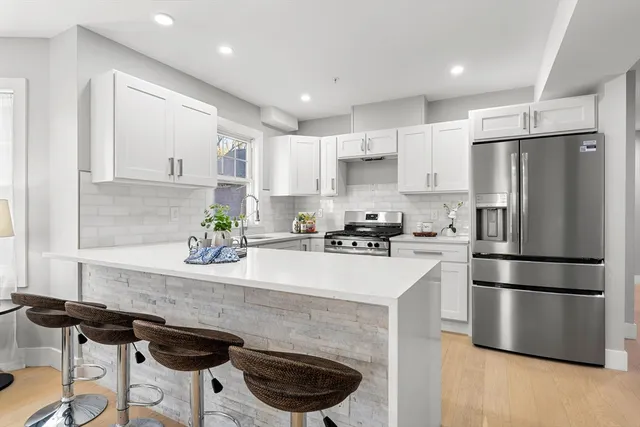 a kitchen with a refrigerator a stove a sink and white cabinets with wooden floor