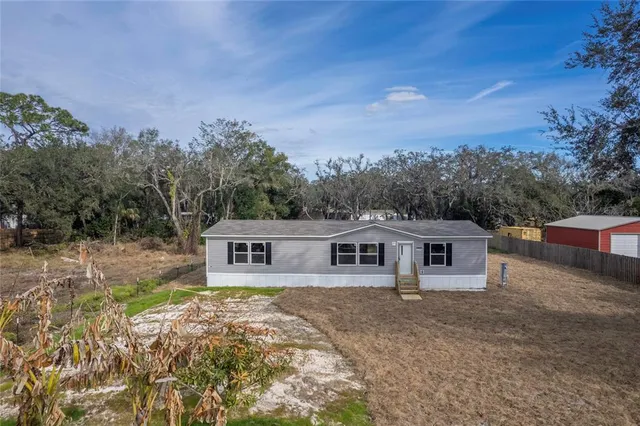 a view of a house with backyard and trees in the background