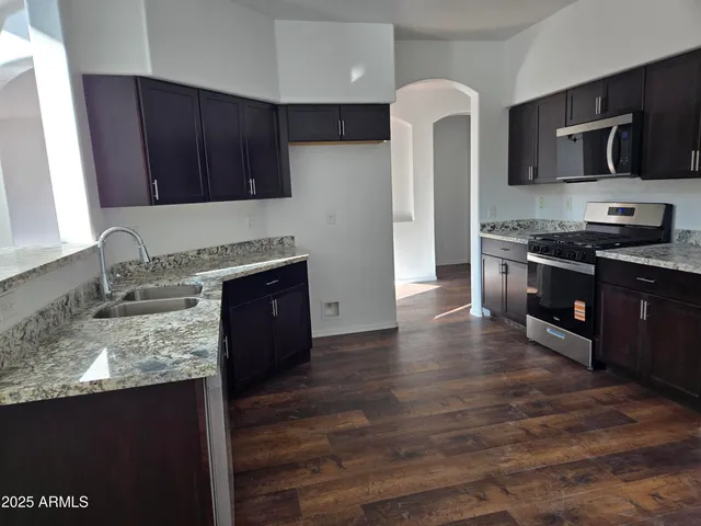 a kitchen with stainless steel appliances granite countertop wooden cabinets and a stove top oven
