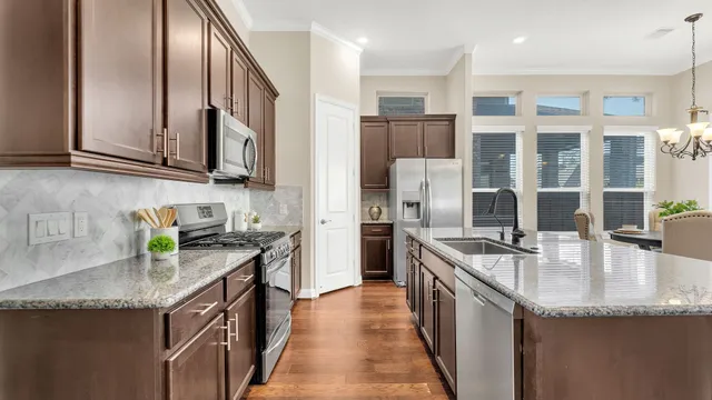 a kitchen with granite countertop stainless steel appliances a sink stove and cabinets