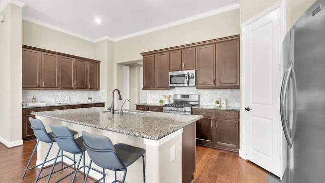 a kitchen with kitchen island granite countertop a table chairs microwave and refrigerator