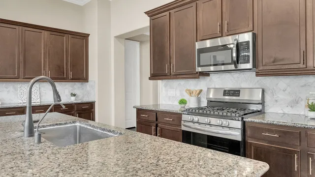 a kitchen with stainless steel appliances granite countertop a sink stove and microwave