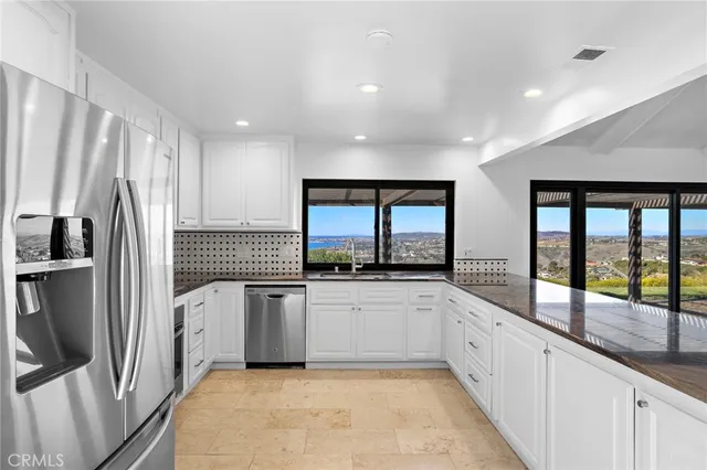 a large kitchen with stainless steel appliances a sink and a large window
