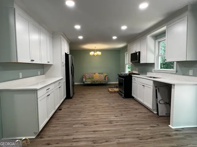 a kitchen with granite countertop a sink stainless steel appliances and white cabinets