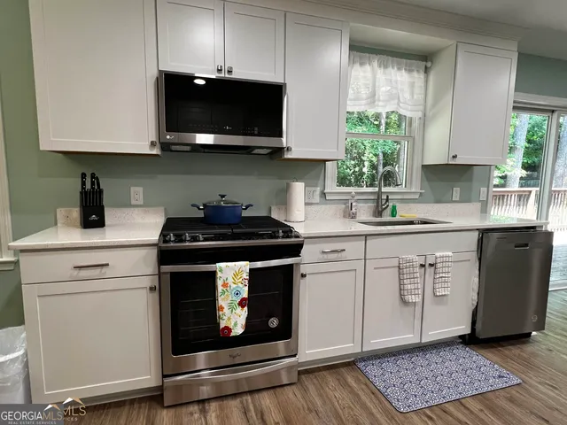 a kitchen with stainless steel appliances a stove a microwave a sink and cabinets