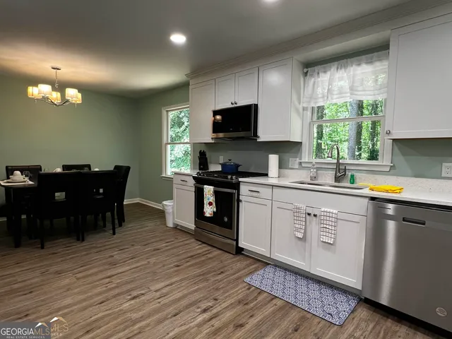 a kitchen with a sink wooden floor dining table chairs and a window