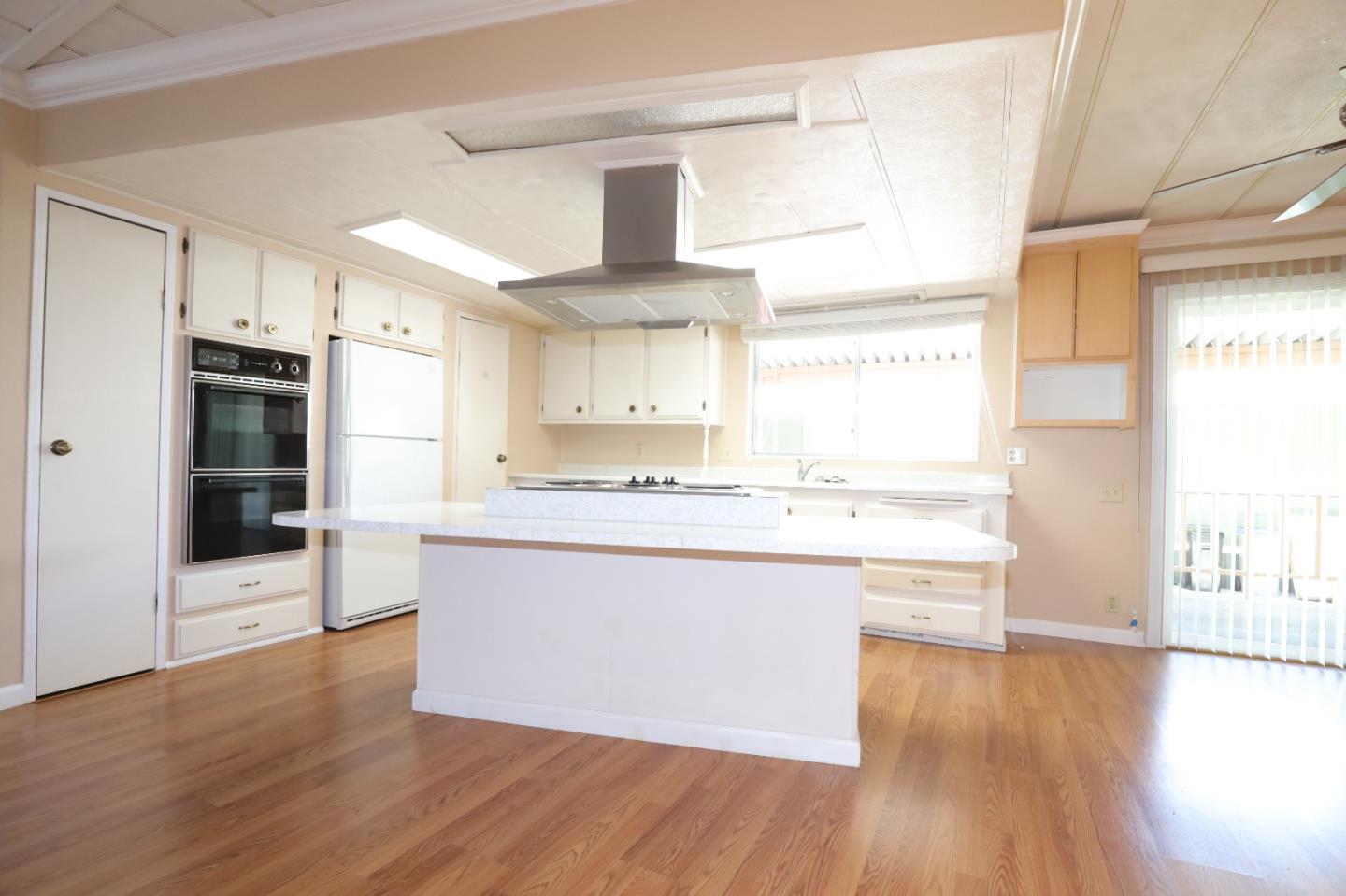 61 Quail Hollow Drive, Unit 61 San Jose, CA 95128 - Photo 8 of 36 a large kitchen with kitchen island a sink a stove a refrigerator and white cabinets with wooden floor