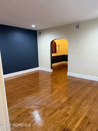 a view of an empty room with window and wooden floor